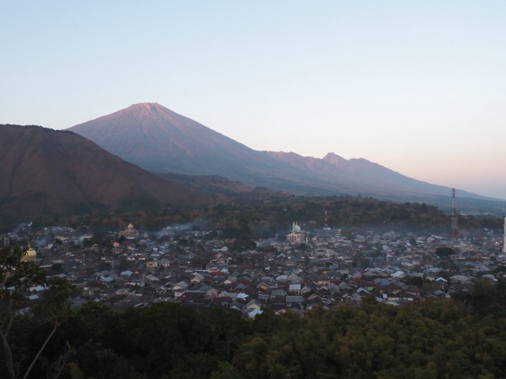 Mount Rinjani rising above a village at sunrise